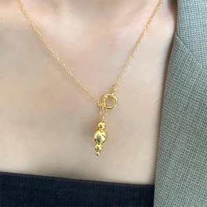 Detail shot of a minimalist gold layered bead pendant necklace on a female model