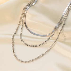 Close-up of triple-layered silver titanium steel necklace on soft beige silk