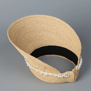 Detail view of woven straw sun hat with decorative white pearls and black elastic inner band