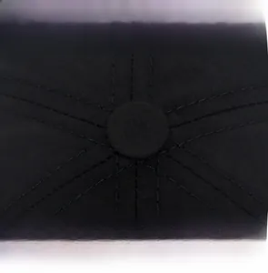 Dettaglio della parte superiore di un cappellino nero con cuciture doppie e bottone centrale
