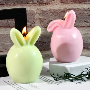 Easter bunny candle molds set with lit pink and green rabbit candles on vintage background