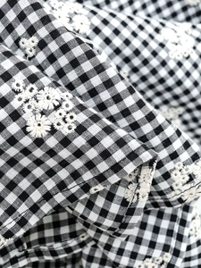 Détail de tissu vichy noir et blanc avec broderie florale haut de gamme et texture tissée