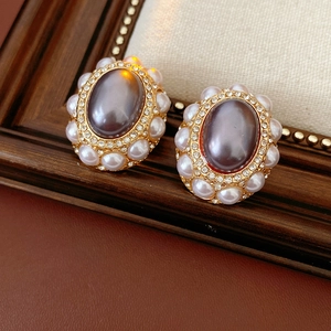 Macro shot of vintage oval earrings with grey pearl and rhinestones on leather background