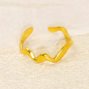 Close-up of golden wavy adjustable ring showing polished metal texture on beige fabric