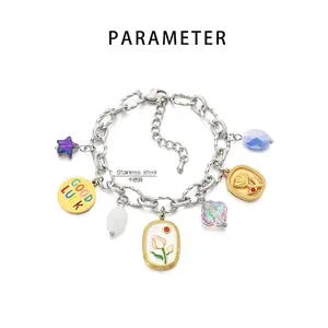 Detailansicht eines Edelstahl-Charm-Armbands mit Sonnen-, Stern- und Glücksanhängern