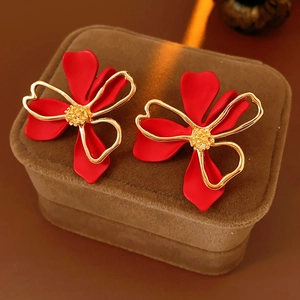 Detail of red floral earrings with gold edges on a brown velvet jewelry box base