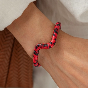Macro shot of wavy irregular bangle featuring a red and black textured leopard pattern