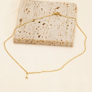 Macro shot of gold letter A pendant on a thin O-chain over limestone texture