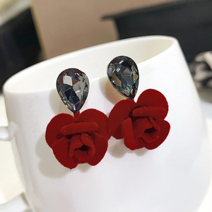 Detail of red flocked rose earrings with dark grey gemstones on a white cup edge