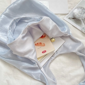 Detail of light blue satin tote bag with glossy silk texture and spacious interior