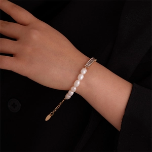 Detail of elegant pearl bracelet with zircon inlay worn over black suit sleeve