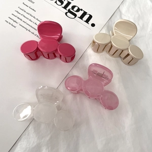 Pink and beige Mickey-shaped hair claws on white fabric with fashion magazine