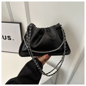 Close-up of black pleated dumpling bag with elegant silver chain strap being held