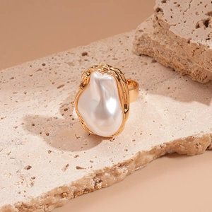 Detailed view of baroque pearl inlay within textured gold-plated irregular oval ring
