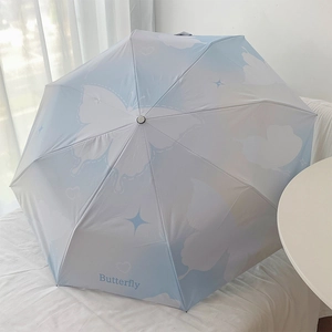 Detail of blue and white gradient umbrella with butterfly and cloud patterns for sun protection