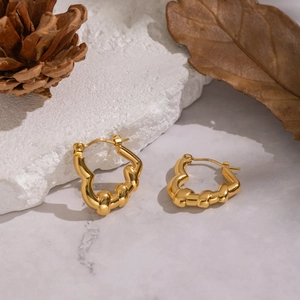 Detailed macro view of 18K gold plated twisted hoop earrings on white stone background