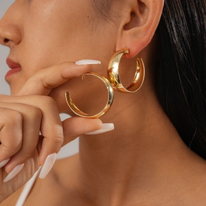 Detailed close-up of chunky gold-layered geometric earrings worn by a female model
