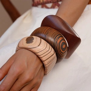 Close-up of stacked vintage wood grain resin bangles on a model's wrist with linen fabric
