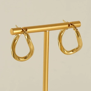 Golden irregular twisted hoop earrings on a T-bar display stand with soft shadows