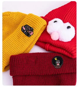Detail of colorful knitted beanies featuring hip-hop cartoon girl badges and plush decor