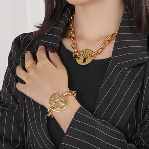 Detailed view of chunky gold chain necklace and bracelet with Tree of Life charms