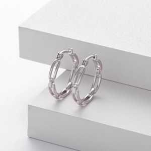 Macro shot of S925 sterling silver chain link earrings on a minimalist white stand