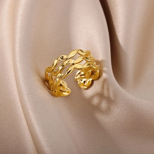Macro shot of gold-plated open ring with triple woven texture on silk fabric