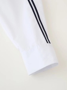 Detail of white cotton shirt sleeve featuring black double-stripe decorative webbing trim