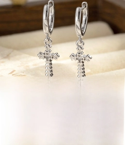 Détail macro de boucles d'oreilles croix en argent avec zircons et anneau de 8mm