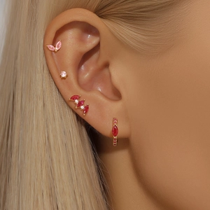 Close-up of S925 silver gold-plated stud earrings set with pink and red gems on an ear