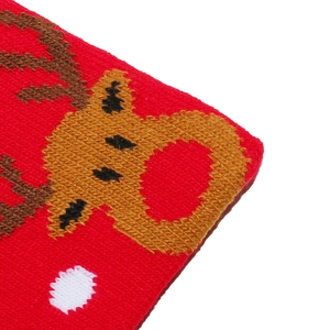 Macro detail of red knitted Christmas hat with reindeer pattern and snowflake weave