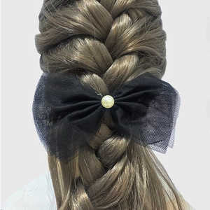 Elegant black lace bow hair clip with pearl detail shown on a braided hairstyle
