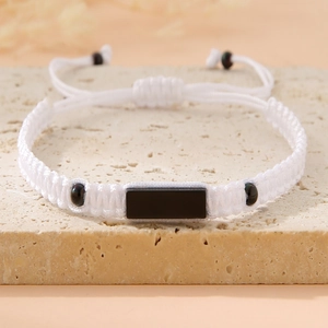 Detail of adjustable white braided bracelet with central black rectangle accent