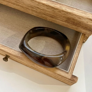 Macro shot of thick amber marble resin bangle with tortoiseshell texture in a wooden box