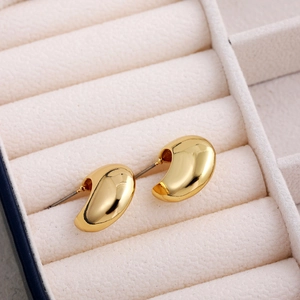 Macro detail of polished 18K gold-plated teardrop stud earrings in a jewelry box