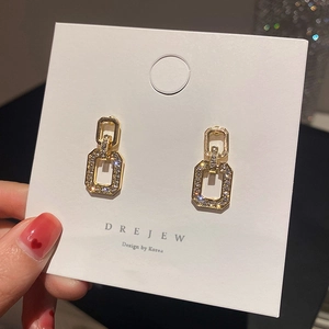 Detail of gold geometric square drop earrings with micro-set white zircon stones