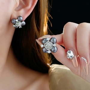 Detailed view of silver flower earrings featuring dark grey pearls and sparkling zircon