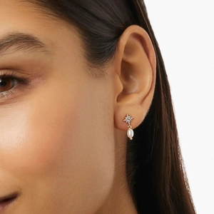 Detailed close-up of an elegant gold star earring with a white pearl on a model