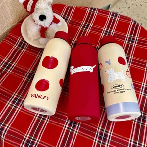 Three stainless steel thermal bottles with red apple and dachshund patterns on plaid background