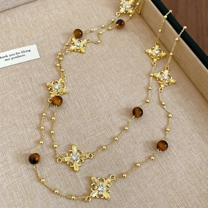 Detailed macro view of vintage gold cross necklace with tiger eye beads on linen tray
