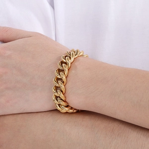 Close-up of gold Cuban link bracelet with engraved skull pattern on punk steel chain