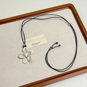 Close-up of silver flower pendant with heart center on adjustable black cord necklace