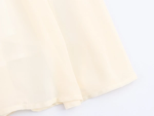 Detail of light beige chiffon dress hem showing fabric texture and sewing quality
