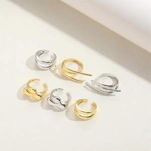 Artistic layout of multiple 14K gold and silver chunky rings on beige texture background