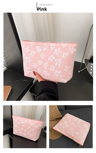 Detailed close-up of pink fabric makeup bag with white 3D floral embroidery and zipper