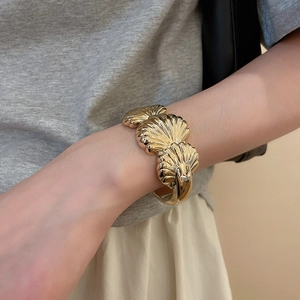 Close-up of golden irregular textured shell bracelet on model's wrist with vintage finish