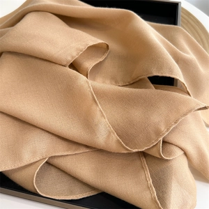 Close-up of soft beige cotton linen scarf showing delicate texture and elegant folds