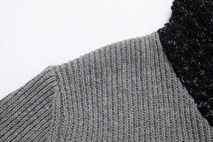 Dettaglio ravvicinato della trama in maglia grigia e nera del maglione da uomo