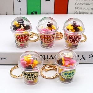 Close-up of five mini popcorn cup keychains with golden rings on a bright table