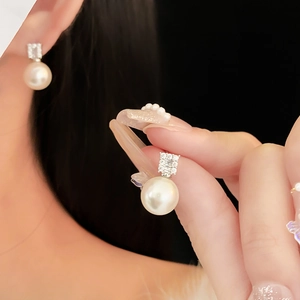 Detailed view of elegant pearl stud earrings featuring zircon embellishments on ear